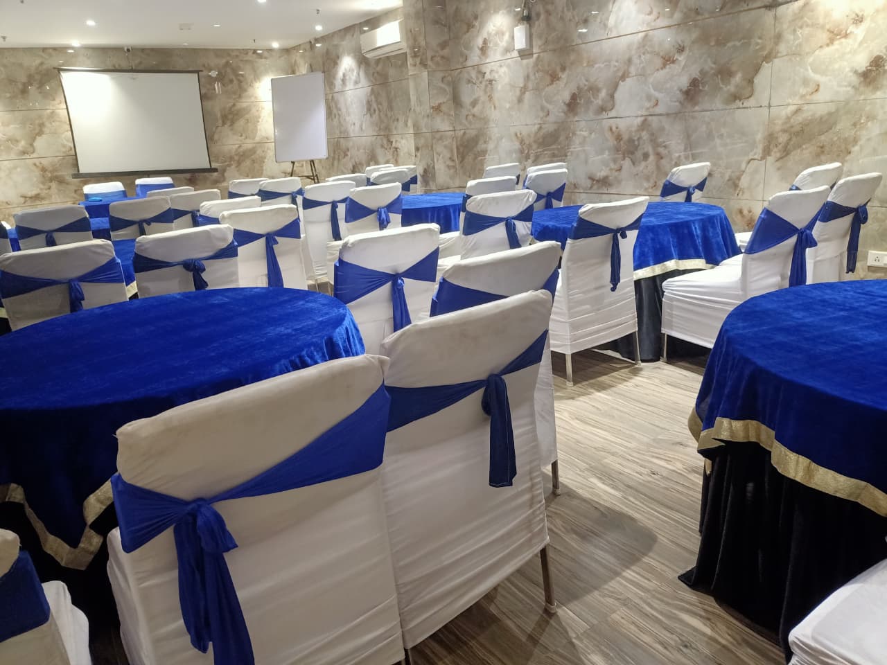 Hall 1 set up in classroom style with round tables, covered chairs and a projector screen